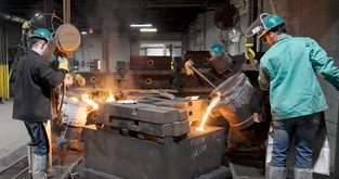 Los empleados de Astech vierten acero fundido en un moldes de arena producido con patrones impresos en 3D.
